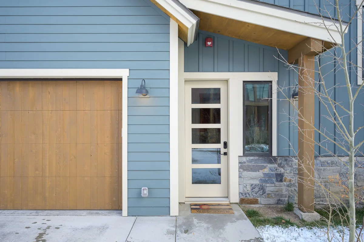 This exterior image features the villa's main entrance with a prominent wooden door, garage, and stone accents, creating a welcoming first impression for arriving guests. The setting suggests a home designed for gatherings and group arrivals.